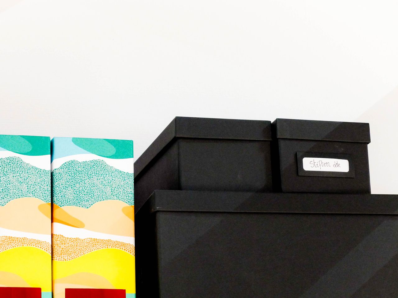 brand-02 A stack of colorful and black storage boxes neatly arranged on a shelf.